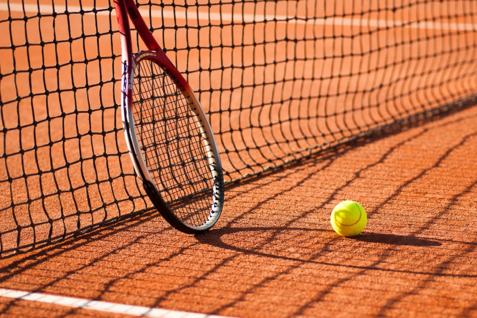 TC 1913 Düsseldorf e. V. - Ein Tennisschläger lehnt an einem Tennisnetz, ein Tennisball liegt unweit daneben